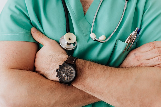 a medical professional in blue scrubs with a stethoscope around their neck